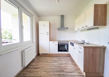 Helle Einbauküche mit Holzoptik-Arbeitsplatten, modernen Geräten und großem Fenster.
