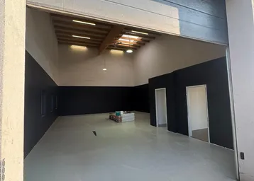 Geräumige Garage mit hohen Decken, freiliegenden Holzbalken und einem großen Rolltor.