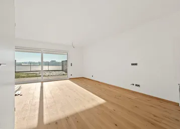 Helles Wohnzimmer mit neuem Parkettboden und großem Schiebefenster zum Außenbereich.