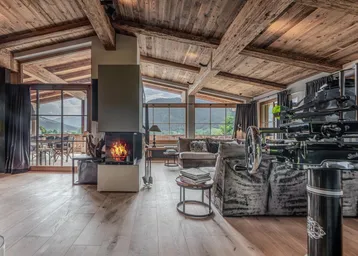 Geräumiger Wohn- und Essbereich mit Kamin, Holzbalkendecke und großen Fenstern mit Bergblick.