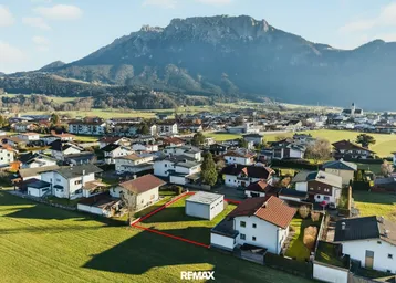 Luftaufnahme eines Baugrundstücks in einer ländlichen Wohngegend mit malerischem Bergblick.