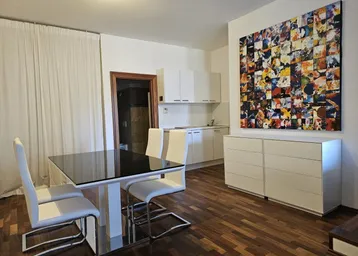 Heller offener Wohn-Essbereich mit integrierter Küchenzeile und modernem Kunstwerk an der Wand.