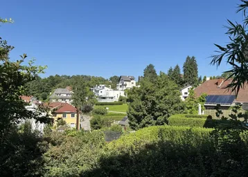 Weitläufiger Blick über die grüne Wohngegend mit weiteren Häusern und klarem Himmel.
