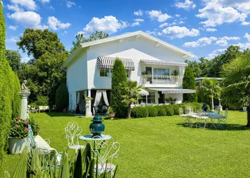 Weitläufiger Garten mit gepflegtem Rasen, Palmen und eleganten Sitzgelegenheiten vor dem Haus.
