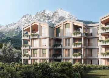 Modernes Wohngebäude mit alpiner Architektur und Bergblick, umgeben von grüner Landschaft.