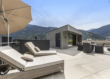 Dachterrasse mit Liegestühlen und Essbereich, bietet einen weiten Blick auf die umliegende Bergwelt.