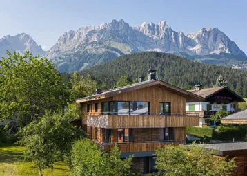 Modernes Holzhaus mit traditioneller Architektur und beeindruckendem Bergblick in alpiner Umgebung.