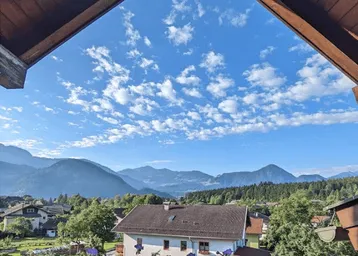 Panoramablick auf die umliegende Berglandschaft und grüne Natur von einem Balkon aus.