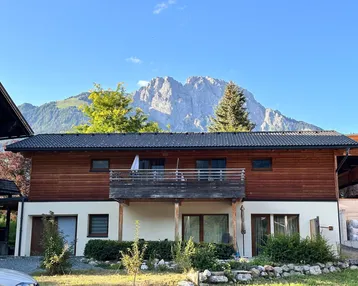 Charmantes Haus mit Holzelementen, Balkon und atemberaubendem Bergblick in ländlicher Umgebung.