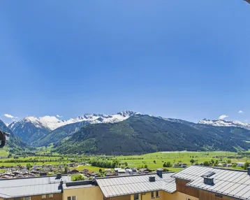 Spektakulärer Bergblick von einem Balkon mit grünen Tälern und schneebedeckten Gipfeln.