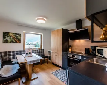 Moderne Küche mit Holzelementen, Essbereich und Blick auf die umliegende Landschaft.