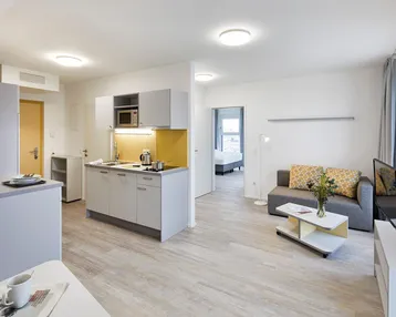 Helles, offenes Wohn-Esszimmer mit integrierter Küchenzeile und modernem Design.