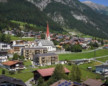 Luftaufnahme eines malerischen Dorfes in den Bergen mit traditionellen Häusern und einer Kirche.