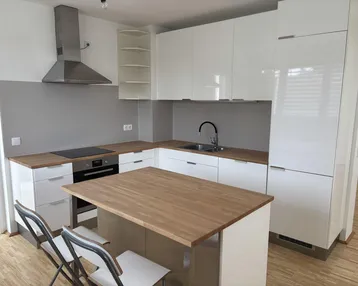 Moderne Küche mit weißen Hochglanzfronten, Holzarbeitsplatten und einer Kücheninsel mit Sitzgelegenheiten.