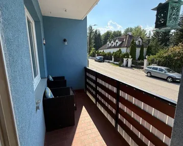 Blauer Balkon mit Terrakotta-Fliesen, Sitzgelegenheiten und Blick auf die Straße.