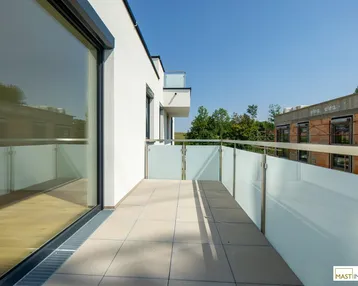 Moderner Balkon mit Fliesenboden und Milchglasgeländer, bietet einen weiten Blick in die Umgebung.