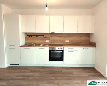 Moderne Einbauküche mit weißen Hochglanzfronten, Holzoptik-Arbeitsplatte und integrierten Geräten.