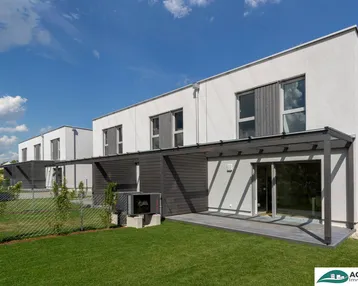 Moderne Reihenhäuser mit privatem Garten und überdachter Terrasse unter blauem Himmel.