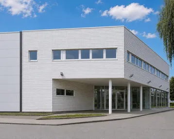 Modernes Geschäftsgebäude mit weißer Fassade, großen Fenstern und einem einladenden Eingangsbereich.
