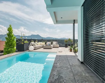 Große Dachterrasse mit Infinity-Pool, gemütlicher Lounge und atemberaubendem Bergblick.