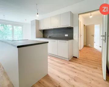 Moderne offene Küche mit Kücheninsel, hellen Schränken und Zugang zum Balkon.