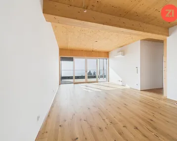 Helles, geräumiges Zimmer mit Holzbalkendecke, Parkettboden und Zugang zu einer Terrasse mit Weitblick.