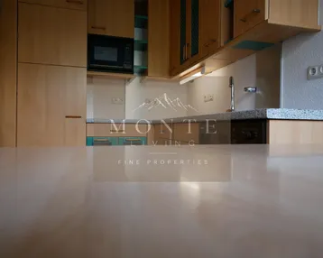 Funktionale Küche mit Holzschränken, Mikrowelle und Arbeitsplatte in Granitoptik.