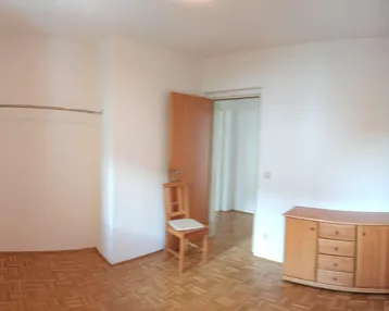 Helles Schlafzimmer mit Parkettboden, Fenster und einem Kleiderständer, bereit zur individuellen Einrichtung.