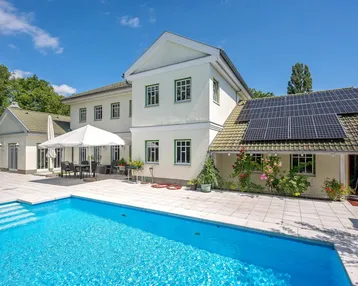 Großzügiger Außenbereich mit Swimmingpool, Sonnenterrasse und Photovoltaikanlage auf dem Dach des Hauses.