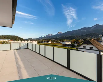 Geräumige Dachterrasse mit Fliesenboden und weitem Blick auf die umliegende Berglandschaft und das Dorf.