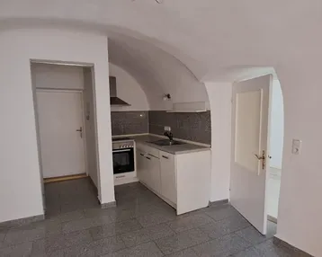 Kleine Küche mit Gewölbedecke und Fliesenboden, ausgestattet mit Herd und Spüle.