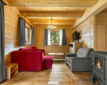 Rustikales Wohnzimmer mit Holzboden, Kaminofen und bequemen Sitzgelegenheiten.