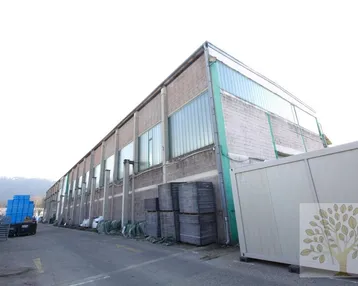 Langes Industriegebäude mit Backsteinfassade und Oberlichtern unter hellem Himmel.