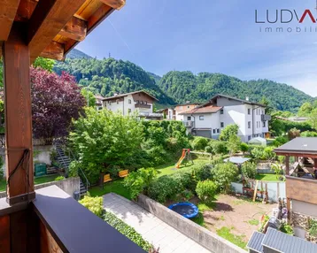 Geräumiger Balkon mit Holzboden und schöner Aussicht auf den Garten und die umliegenden Berge.