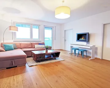 Helles Wohnzimmer mit beigem Ecksofa, Holzboden und einem modernen Wandkamin.