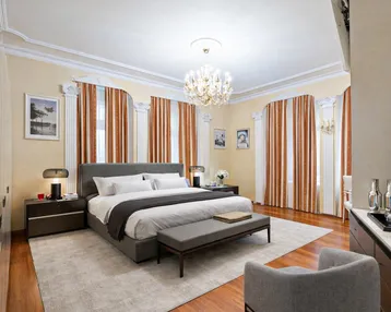Elegantes Schlafzimmer mit großem Bett, Parkettboden und Stuckdecken, ausgestattet mit luxuriösen Vorhängen.