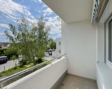 Heller Balkon mit Blick auf die Straße und umliegende Gebäude, ideal für entspannte Stunden im Freien.