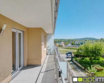 Heller Balkon mit Fliesenboden und Geländer, bietet einen weiten Blick ins Grüne.