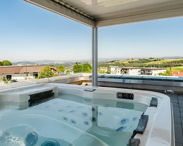 Luxuriöser Whirlpool auf der Dachterrasse mit weitem Blick über die grüne Landschaft.