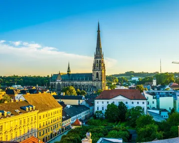 Panoramablick über eine historische Stadt mit einer imposanten Kathedrale und vielfältiger Architektur unter blauem Himmel.