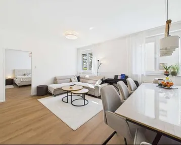 Helles, offenes Wohn- und Esszimmer mit modernem Sofa, Esstisch und Parkettboden.