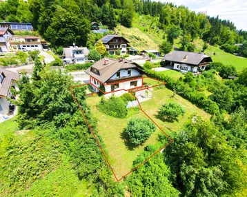 Luftaufnahme des Hauses mit großem Grundstück in grüner Hanglage, umgeben von Bäumen und Natur.