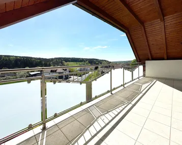 Geräumiger Balkon mit Fliesenboden, Holzdecke und weitem Blick über die Landschaft.