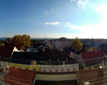 Panoramablick über die Dächer der Stadt mit weitem Horizont unter blauem Himmel.