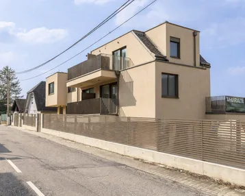 Modernes Mehrfamilienhaus mit mehreren Balkonen und zeitgenössischer Architektur an einer Wohnstraße.