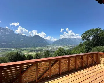 Großer Holzbalkon mit atemberaubendem Blick auf die umliegende Berglandschaft und das Tal.
