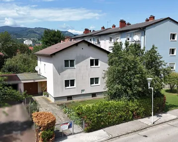 Freistehendes Einfamilienhaus mit Garten und angrenzenden Mehrfamilienhäusern in sonniger Lage.