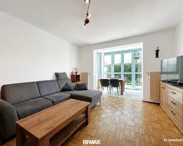 Helles Wohn- und Esszimmer mit Parkettboden, bequemer Couch und Zugang zum Außenbereich.