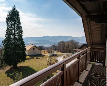 Balkon mit weitem Blick über die grüne Landschaft und die umliegenden Berge.