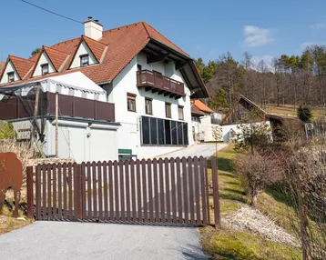 Traditionelles Landhaus mit Satteldach und Holztor, umgeben von ländlicher Natur.